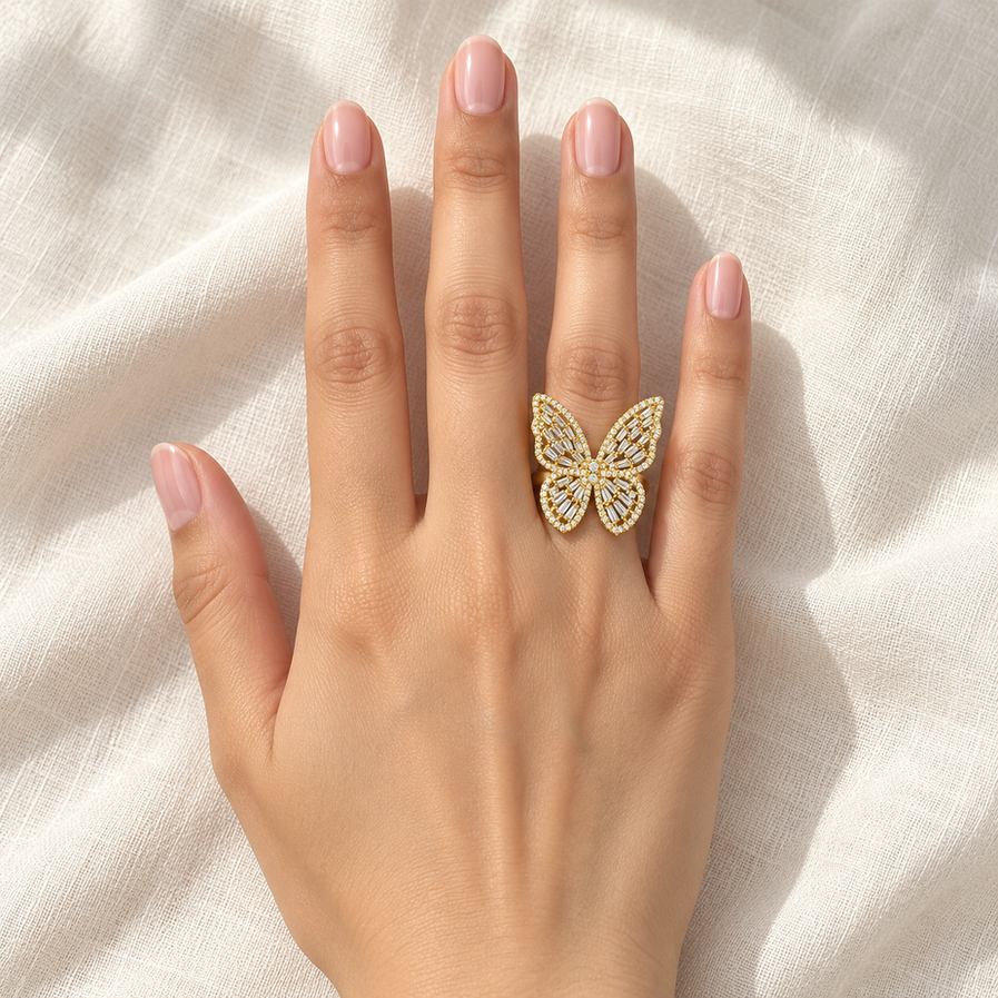 Gold-tone adjustable butterfly ring with clear stone detailing, worn centred on a woman’s finger.