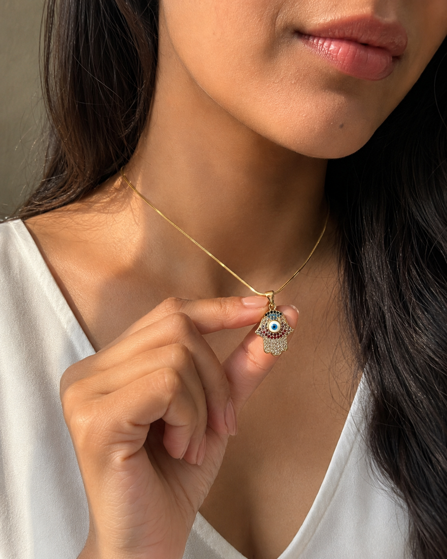 Close-up of a gold-tone Hamsa hand necklace with a blue evil eye on an Indian woman