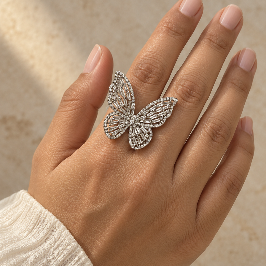 Silver-tone adjustable butterfly ring with clear stone detailing, worn centred on a woman’s finger.