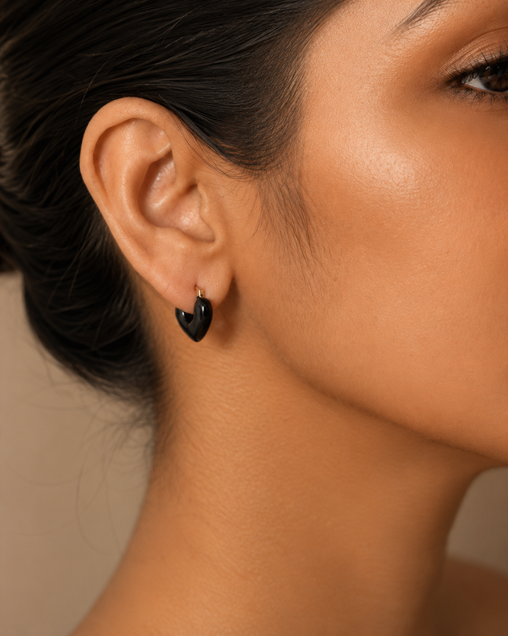Macro close-up of black heart-shaped hoop earring on a model