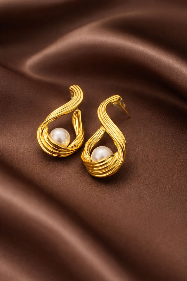 Close-up of silver dangler earrings with abstract swirl shape and pearl