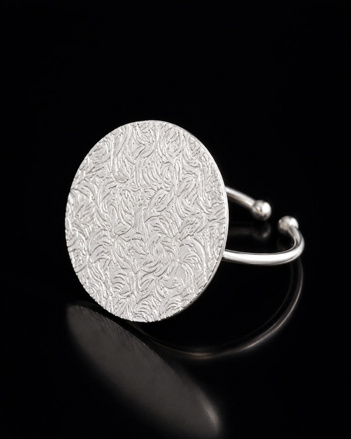 Silver disc brass ring on dark background