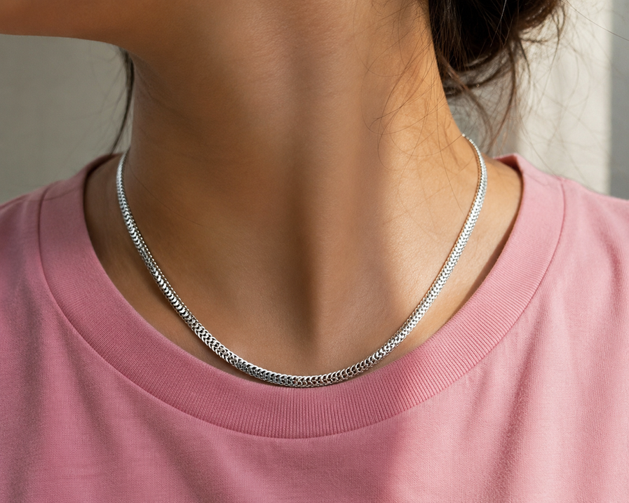 Female model wearing a stainless steel scale-link chain over a pink T-shirt