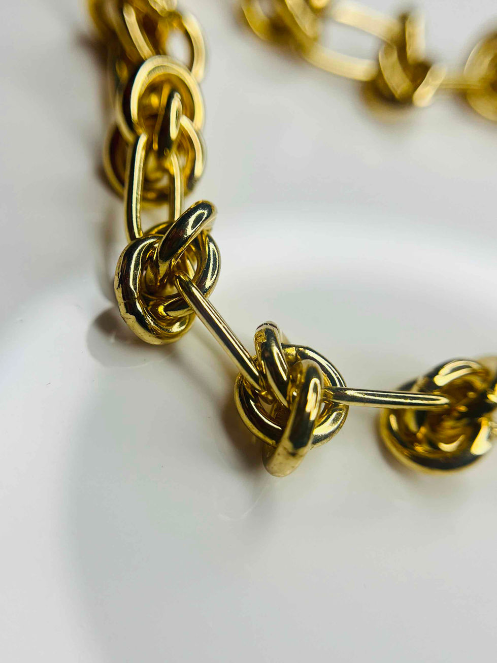 A stunning 18K gold-plated knot-link chain necklace, featuring a series of intertwined golden links with a glossy finish, lai