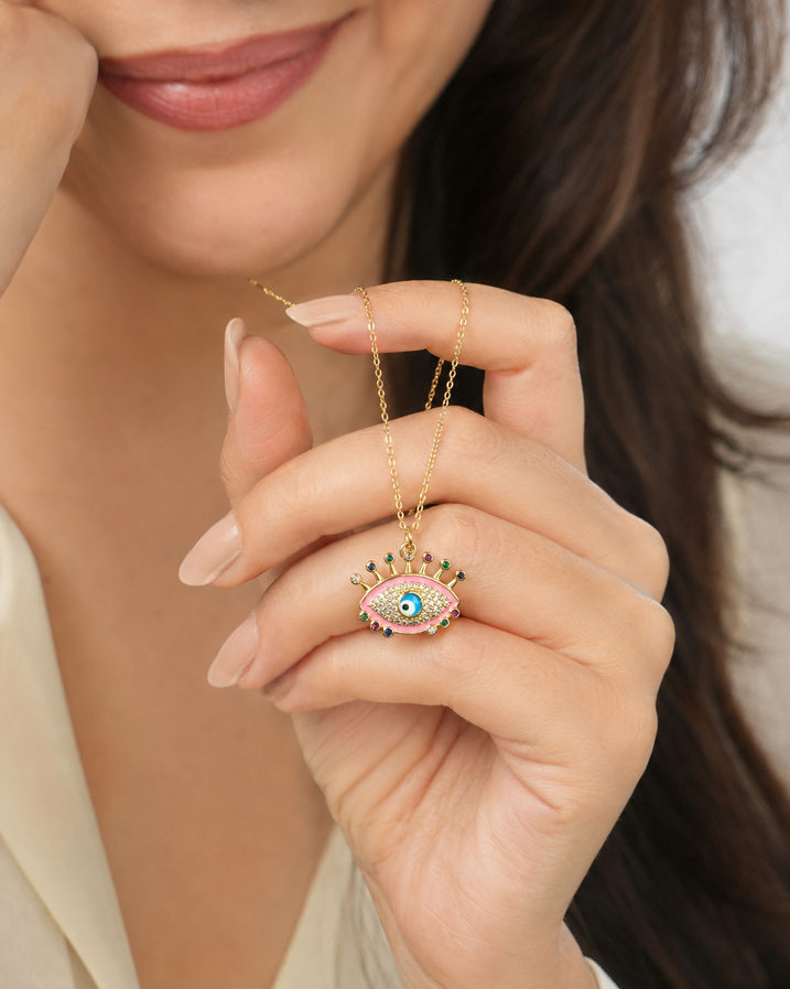 Indian model holding a pink enamel evil eye necklace with multicolour crystal accents