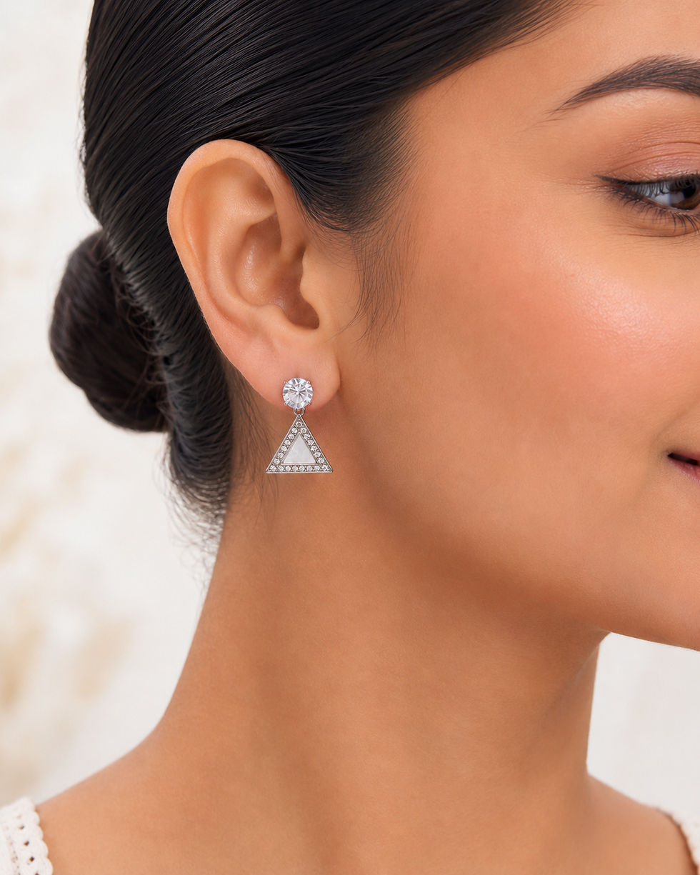 Model wearing silver pyramid stud-drop earrings with crystal-style top and white pearl-look centre.