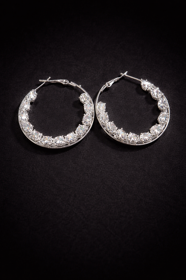 Silver crystal hoop earrings with teardrop stones on black background