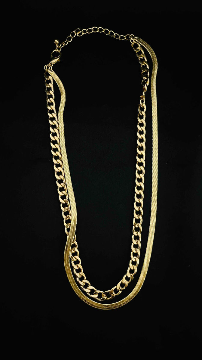 Classic 18K plated Cuban gold chain necklace draped elegantly, showcasing its robust links and lustrous finish against a cont