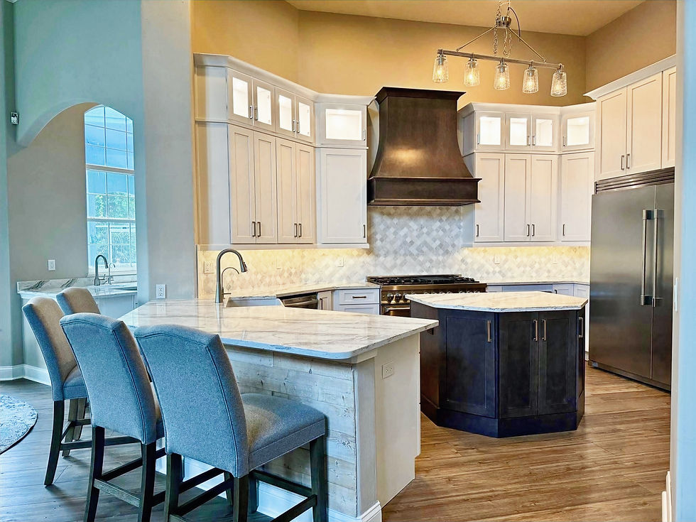 Modern kitchen with grey chairs at a marble island, surrounded by white cabinets and a stainless steel fridge, under warm lighting.