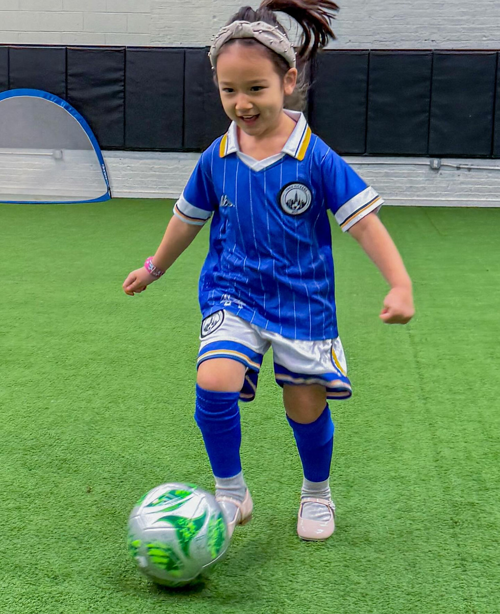 Young girl dribbling a soccer ball during a personalized coaching session