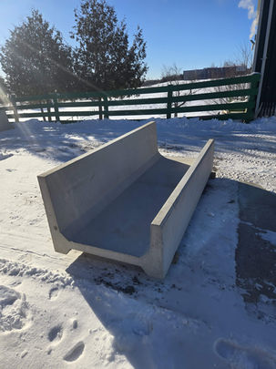 View-con precast concrete large J cattle feed bunk shown outdoors in winter conditions, featuring deep trough and raised side walls.