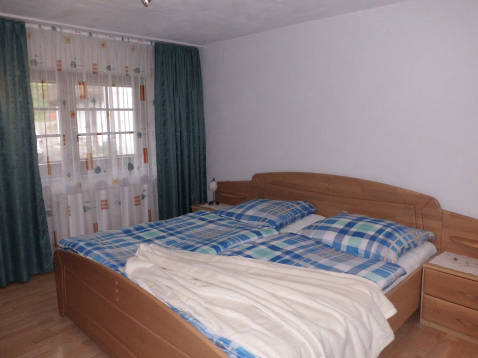 Gemütliches Schlafzimmer mit Doppelbett und blau-weiß karierte Bettwäsche