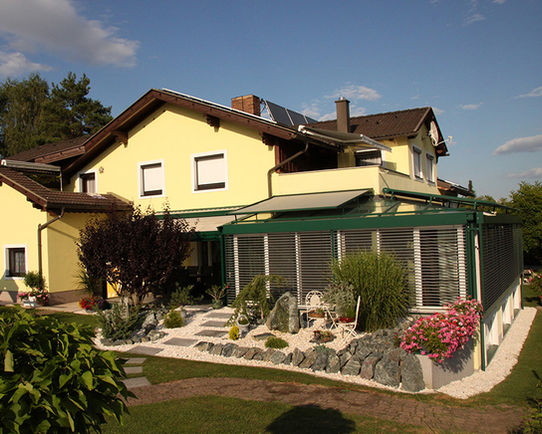 Gelbes Haus mit Wintergarten und Garten