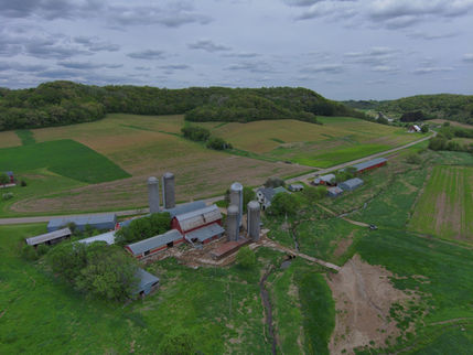 Aerial view of a farm with silos, fields, and a red barn.