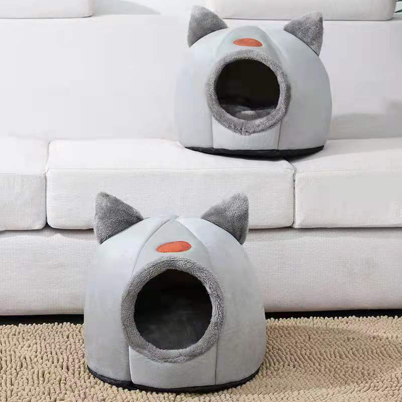 Thumbnail: Two grey cat-shaped winter beds on a white couch and rug.