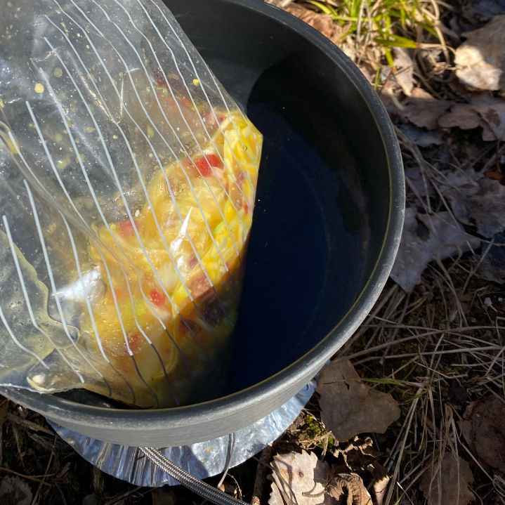 Eggblanding i plastpose oppi vannbad på primus som skal bli til omelett