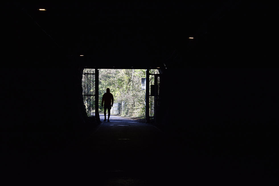Silhouette of a person walking out of a tunnel