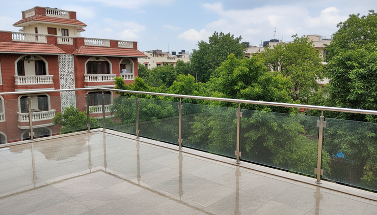 Eye-level view of a terrace with SS304 and toughened glass railings overlooking greenery