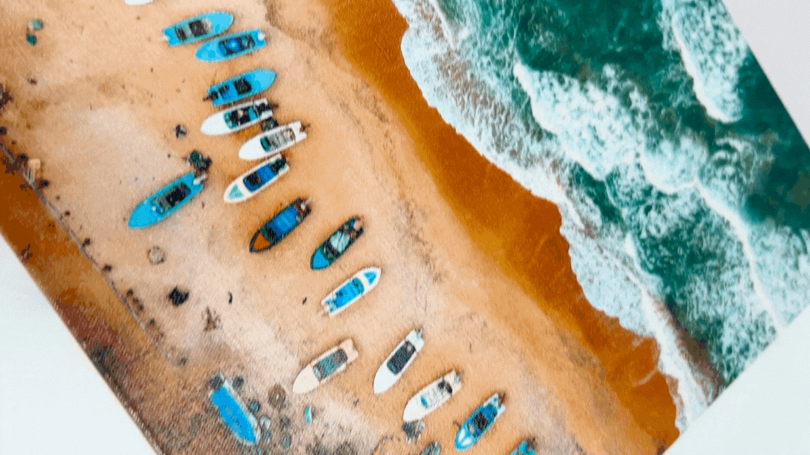 A moving metallic canvas print showing boats on a beach