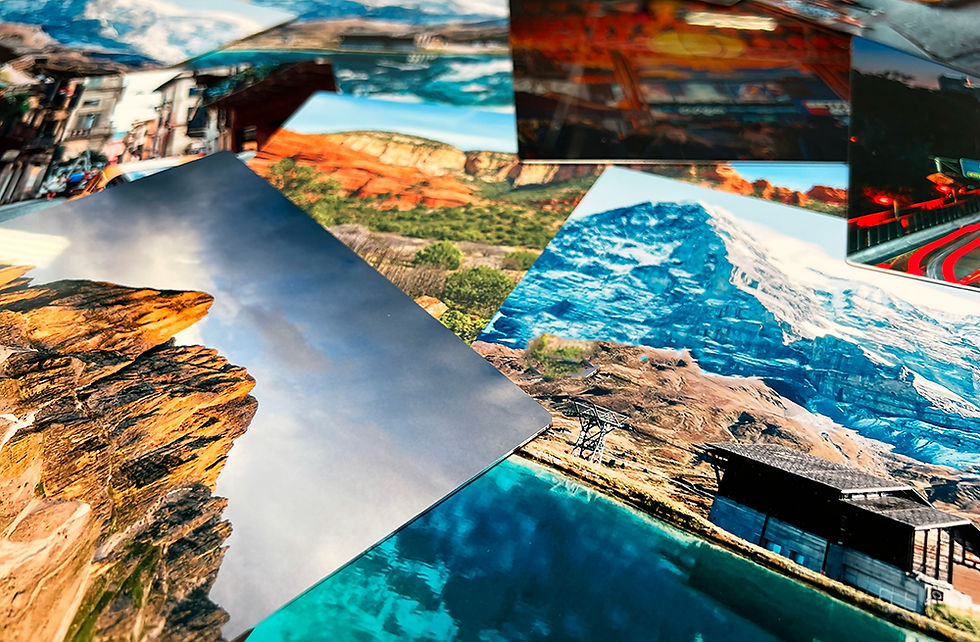 Various colorful HD Metal Prints displaying mountain and landscape scenes, scattered on a surface, creating a vibrant, adventurous mood.