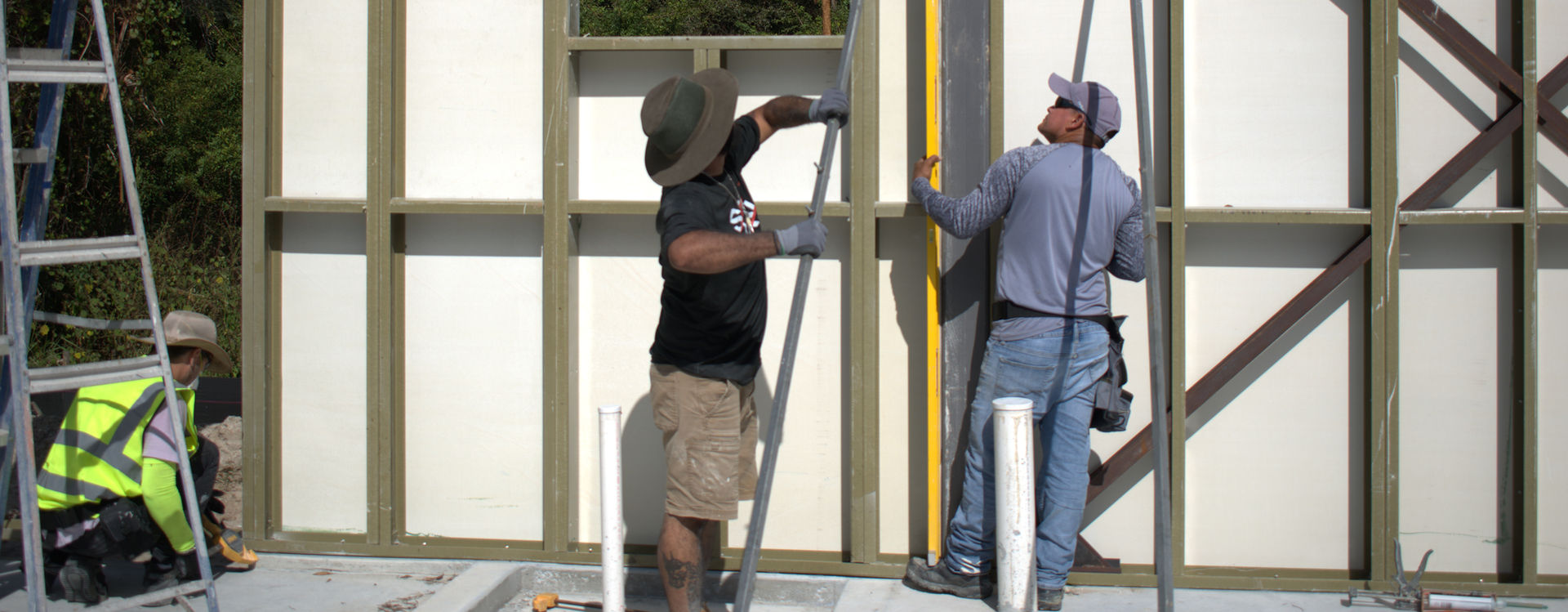 Construction workers installing a pipe on a building frame, working on the project.