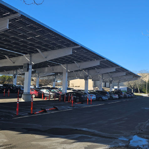 Solar panel canopies over parked cars in a parking lot under blue sky