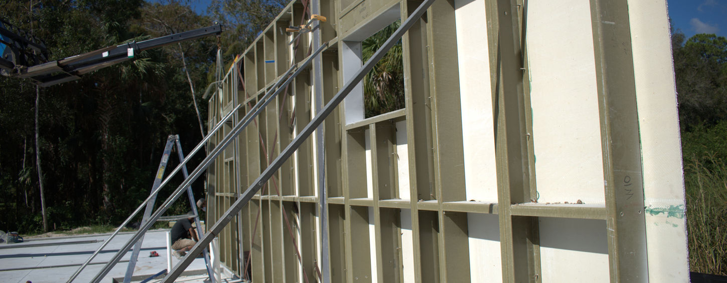 Building construction framing a wall, with scaffolding and support bars, outdoors.