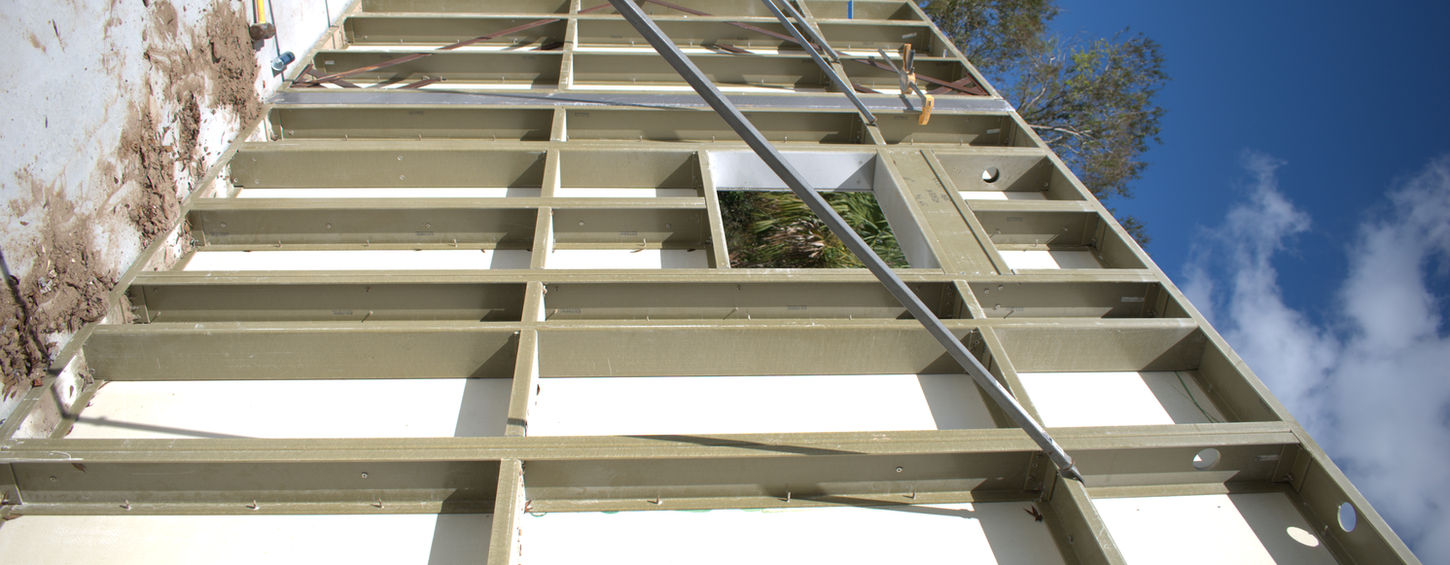 Wooden framework construction with insulation, ladder, and blue sky visible Northstar Building Systems
