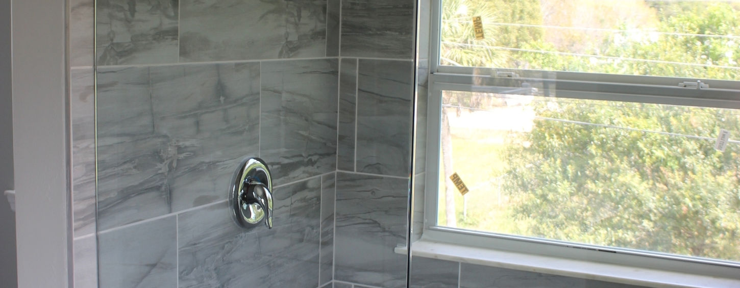 Shower with gray tile and glass door.