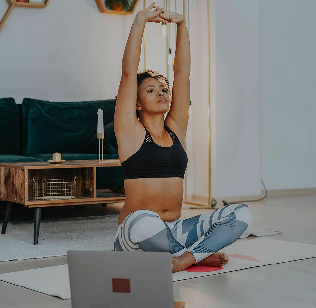 Woman practicing Pilates at home with arms raised