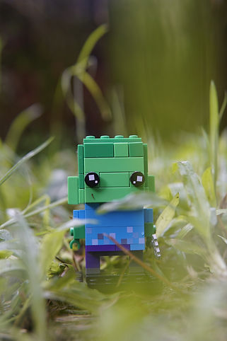A green and blue minecraft figure standing in grass.