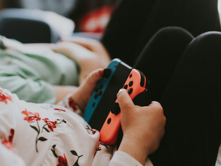 Someone holding a game console controller while relaxing with their knees up.