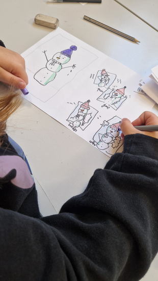 Photo d’un enfant travaillant sur une planche de bande dessinée lors d’un atelier à Maîche, dans le Doubs. L’enfant colorie un bonhomme de neige et illustre une petite histoire sur plusieurs cases avec des détails expressifs.
