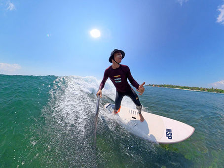 A person SUP-surfing on an ocean wave