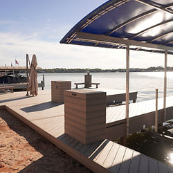Spacious wooden dock with blue canopy overlooking a clear lake.