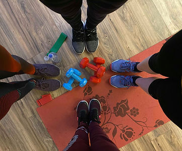 Four women stand over dumbbells
