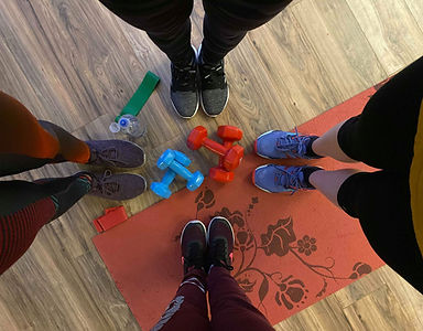 Four women stand over dumbbells