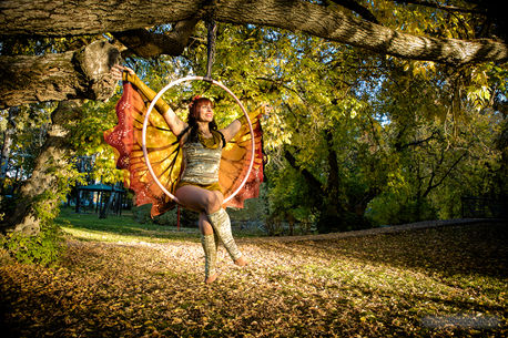 a woman in the park sits on an aerial hoop