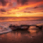 Violin on a sandy beach at sunset with waves washing over it