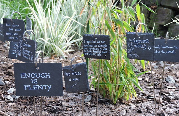 Amoung the plants and soil, grey slate plaques in the foreground have hopes for the climate written on.