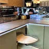 Modern kitchen with a sleek, gray countertop and a corner cabinet featuring a pull-out rotating shelf.