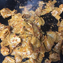 Sizzling, spiced seitan slices in a pan