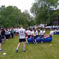 People participating in an outdoor team-building activity on an inflatable tube.