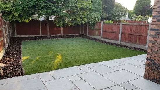 Neat square lawn area surrounded by light-coloured stone paving
