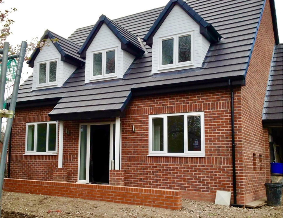 Exterior of a modern red brick house featuring three white gabled dormer windows and a dark tiled roof