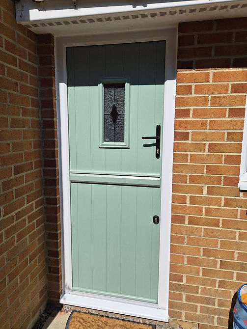 Mint green composite front door with a small window and letterbox set in a red brick wall