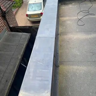 High angle view of a flat roof with fresh lead flashing along the parapet wall edge