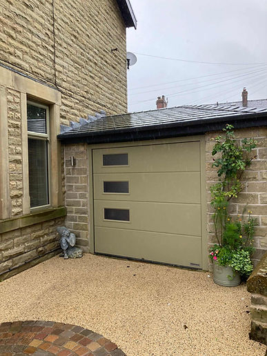 Olive green garage door with square windows on stone building