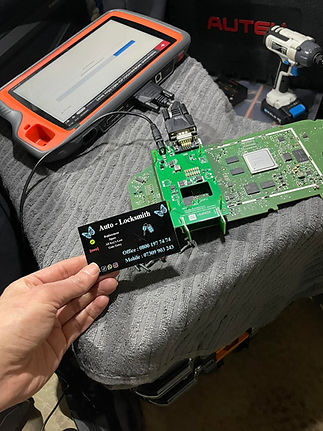 auto locksmith business card in front of electronic circuit boards and a diagnostic device