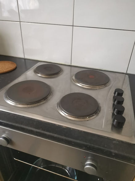 A silver electric stove with four burners on a black counter